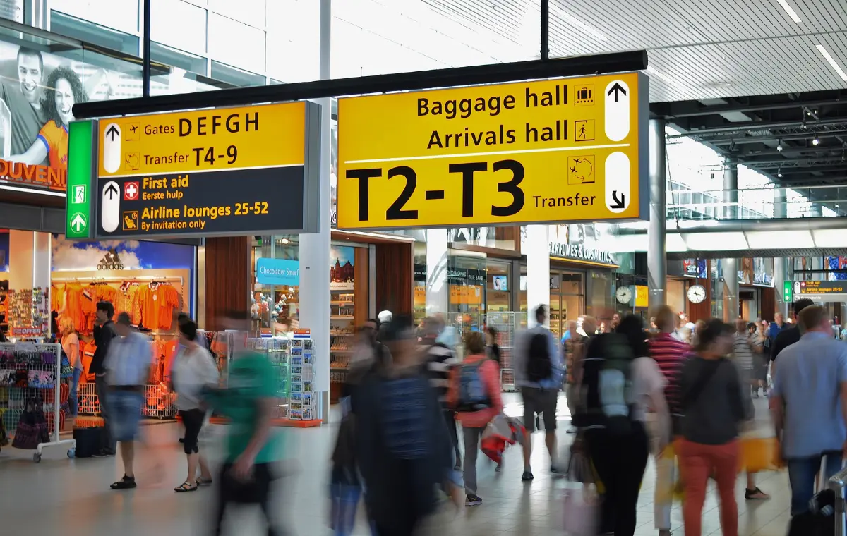 Busy airport departure hall with passengers queuing at brightly lit, generic airline check-in counters.