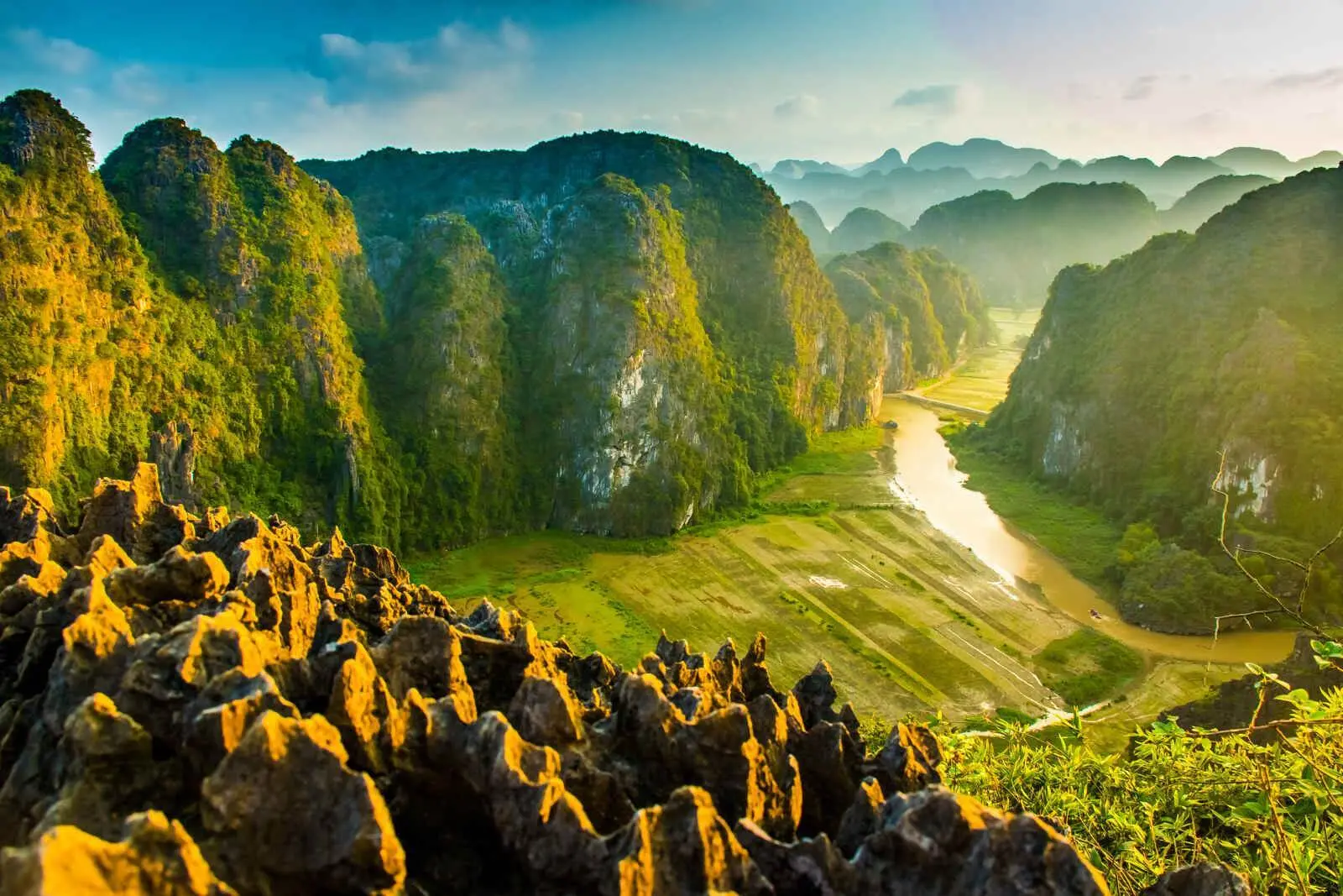 Dramatic limestone karst landscape rising from water and rice fields in Ninh Binh Vietnam.