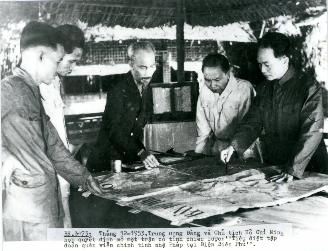 Ho Chi Minh in discussion with Lao Dong Party officials in a simple setting, depicting the leadership circle of North Vietnam during the mid-20th century.