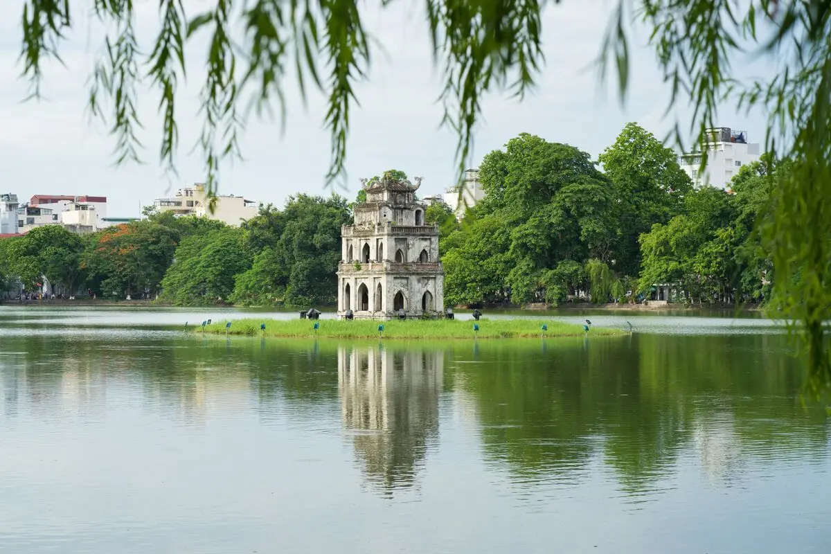 Iconic view of Hoan Kiem Lake in Hanoi featuring the Turtle Tower (Thap Rua) or The Huc Bridge, representing key cultural and scenic aspects of Vietnam's capital city.