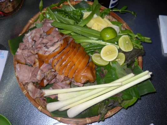 A Vietnamese platter with sliced pork, fresh herbs, lemongrass, and lime
