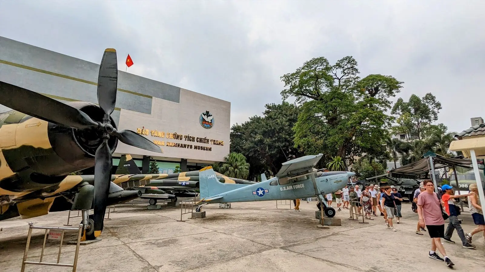 Facade of the War Remnants Museum Vietnam on Vo Van Tan Street, Ho Chi Minh City, with visitors nearby.