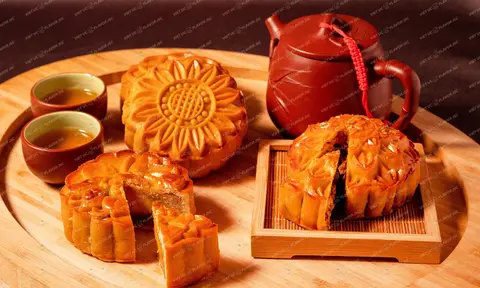 Traditional baked Vietnamese mooncakes (Banh Nuong) arranged on a wooden tray with a teapot and teacups